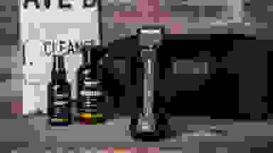 The contents of the Manscaped Perfect Package, which includes the trimmer, two bottles of product, a fake newspaper, and a toiletry bag.