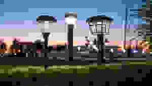 A row of outdoor solar path lights in a park, set against a sunset