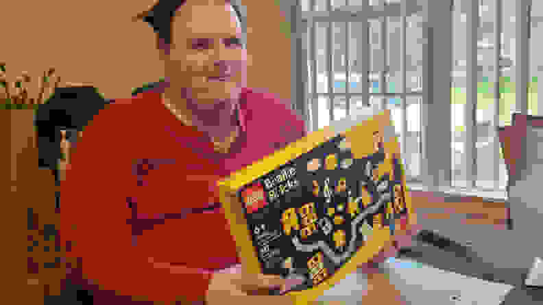 A man holding the Lego Braille Bricks packaging box.