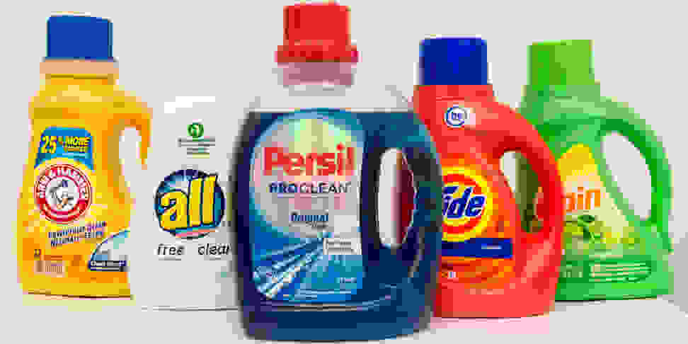 Five bottles of liquid laundry detergent stand in a row
