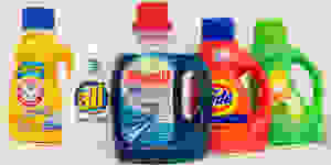 Five bottles of liquid laundry detergent stand in a row