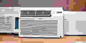 Three of the best window air conditioners are displayed on a wooden countertop, all are white.