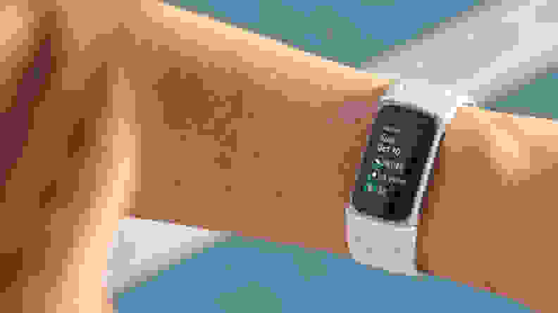A woman looking at the Charge 5 on her wrist.