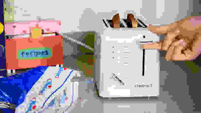 Person adjusting the lever on the Cuisinart 2-slice toaster, filled with two slices of bread.