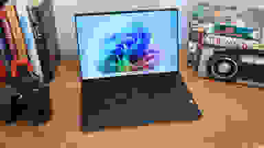 The 2024 Dell XPS 13 9345 laptop sitting on a desk next to a camera and several books.