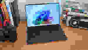 The 2024 Dell XPS 13 9345 laptop sitting on a desk next to a camera and several books.