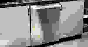A close-up shot of a stainless steel dishwasher installed into a kitchen cabinet.