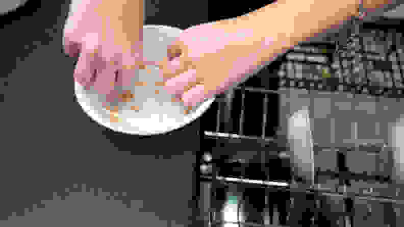 A person measures food stains on a white bowl with a measuring tape