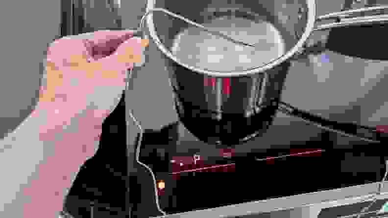 Person holding corded slim thermometer within pot with boiling water on the cooktop of the Frigidaire Gallery GCFI3060BF 30-inch Induction Range.