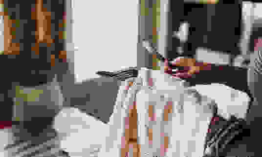 Woman in a kitchen with dish cloth, drying cutlery.