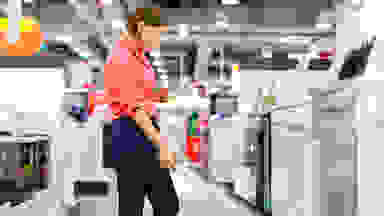A woman examines a dishwasher in a department store.