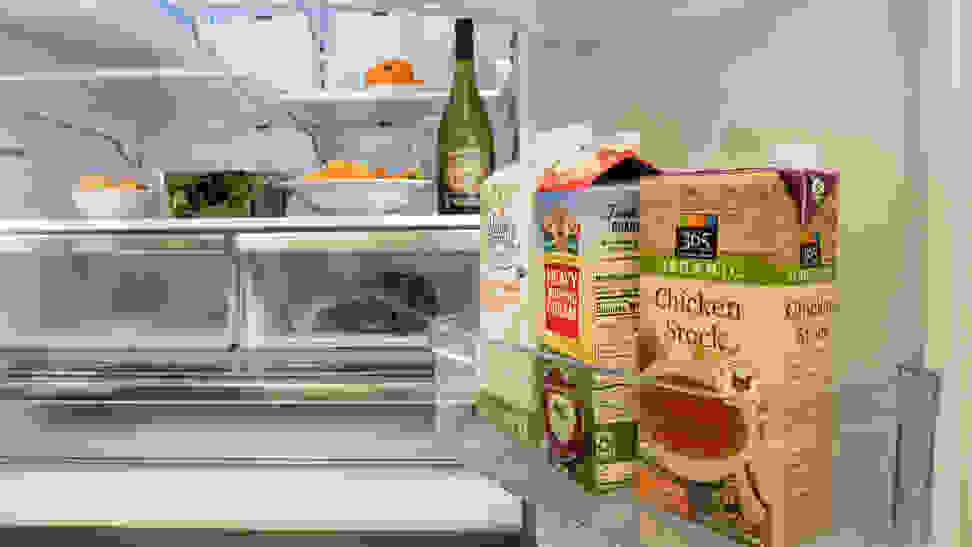 A shot of the interior of a fridge, focusing on its door bins and the lower half of its refrigerator compartment. The fridge is stocked with food.