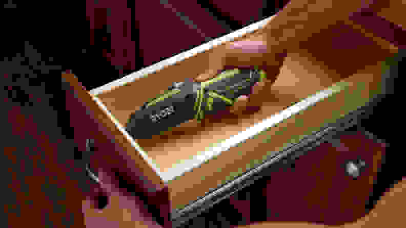 a person uses an electric screwdriver to attach the handle to a cabinet drawer