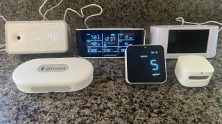 A group photo featuring the six indoor air quality monitors we tested sitting on a countertop