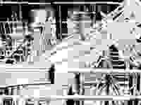 A close-up of a dishwasher's upper rack, showing wine glasses resting in stemware holders.