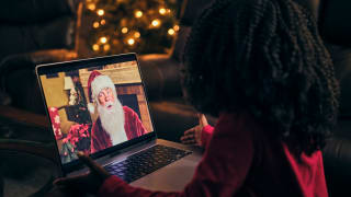 A young child looking at a laptop showing an image of Santa Claus.