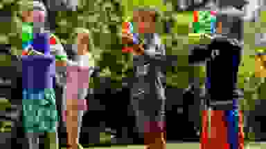 Four kids lined up outside shooting water guns and Nerf Super Soakers