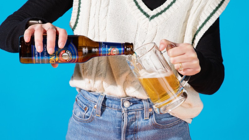 Person pouring a bottle of nonalcoholic beer into a glass