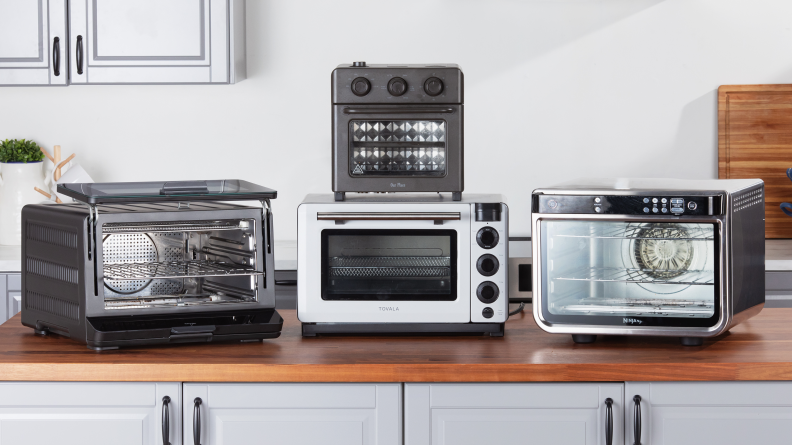 Four countertop ovens, partially stacked, on a kitchen counter