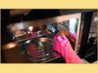 A pink glove cleaning the inside of a microwave
