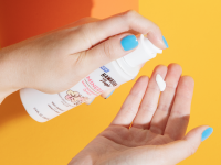 Hawaiian Tropic Milk Sunscreen poured on a woman's hands against a yellow background.