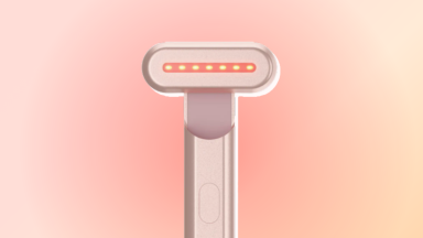 SolaWave Wand in rose gold against a red and orange background